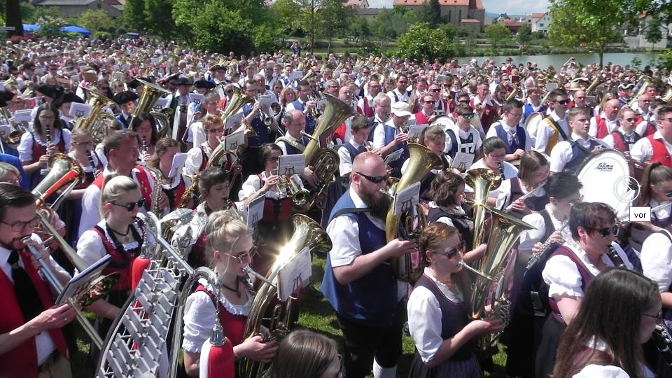 Ein beeindruckendes Bild: Mehr als 1000 Musikanten auf dem Festplatz in Hohenroth, vor dem idyllischen See und der Pfarrkirche. Foto: Brigitte Chellouche Ein beeindruckendes Bild: Mehr als 1000 Musikanten auf dem Festplatz in Hohenroth, vor dem idyllischen See und der Pfarrkirche. Foto: Brigitte Chellouche